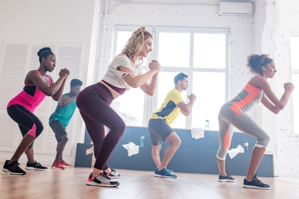 Side view of smiling multiethnic dancers warming up before practicing zumba in studio