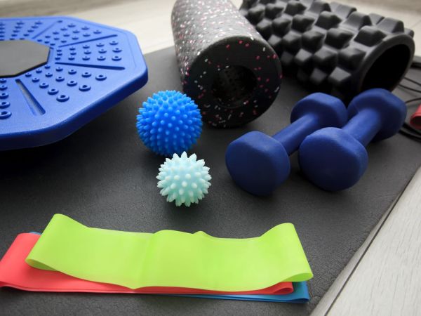 A lot of different fitness and sport accessories and equipment on the wooden floor at home